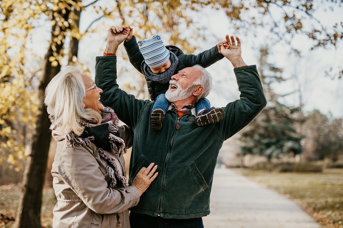 Grandparents walking through a park with their grandson